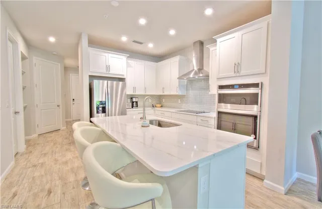 a kitchen with stainless steel appliances kitchen island granite countertop a refrigerator and a sink