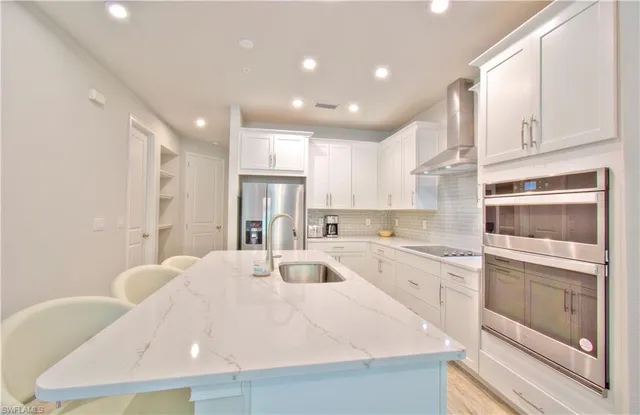 a kitchen with a sink dishwasher a stove and white cabinets with wooden floor