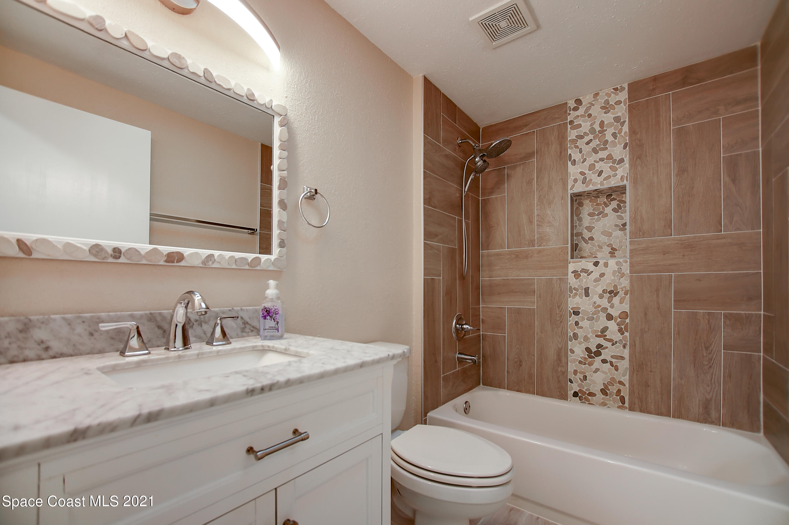 1896 Keewin Avenue Palm Bay, FL 32905 - Photo 16 of 23 a bathroom with a granite countertop toilet a sink a mirror a bathtub and shower