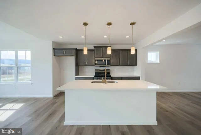 a large room with kitchen island a sink wooden floor and glass door