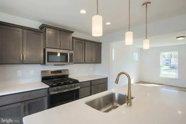 a kitchen with stainless steel appliances granite countertop a sink a stove a microwave a counter space and cabinets