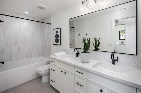 a bathroom with a granite countertop sink a toilet and a large mirror