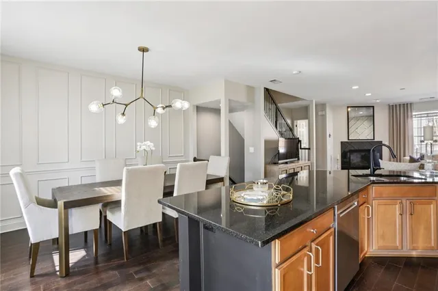 a view of a dining room and livingroom with furniture wooden floor kitchen chandelier