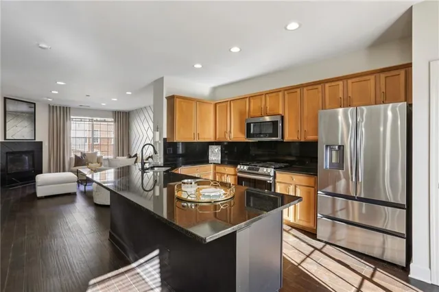 a kitchen with stainless steel appliances granite countertop a refrigerator a stove and a sink with wooden floor