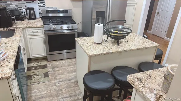 a kitchen with granite countertop a stove a sink and a white wooden cabinets