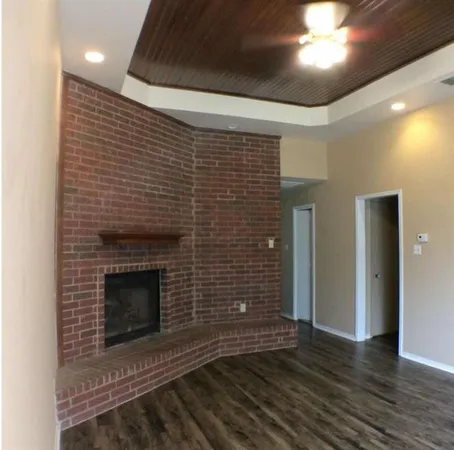 a view of an empty room with wooden floor and a fireplace