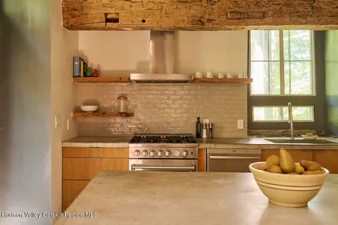a living room with stainless steel appliances kitchen island granite countertop a stove and a large window