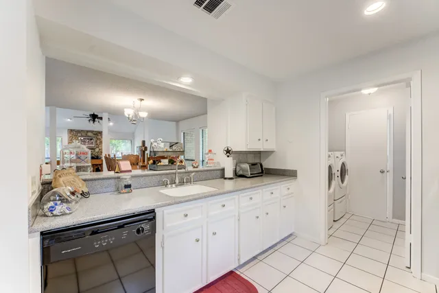 a kitchen with a sink dishwasher and white cabinets with wooden floor