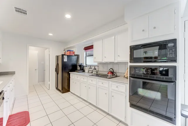 a kitchen with white cabinets and appliances