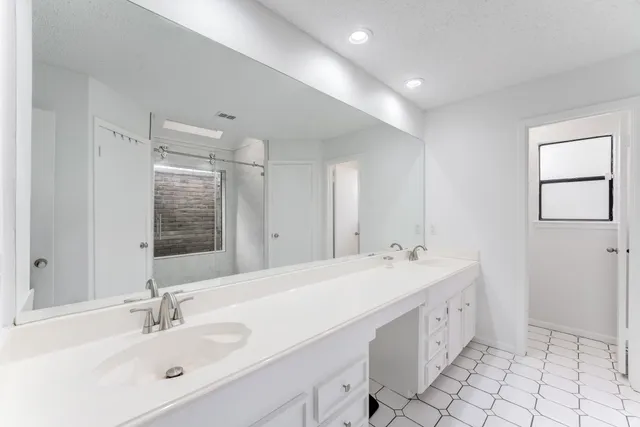 a spacious bathroom with a double vanity sink mirror and bathtub