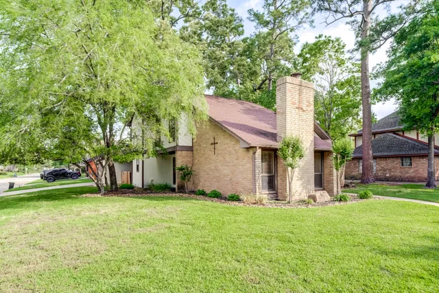 a view of a house with a big yard and large tree
