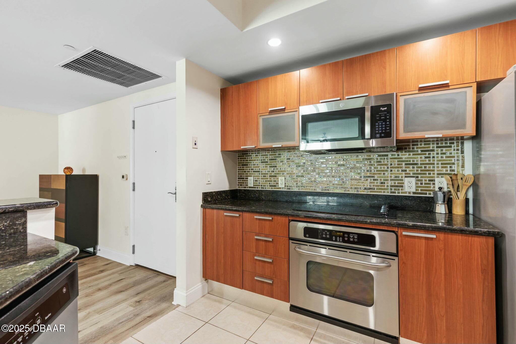 231 Riverside Drive, Unit 1104 Holly Hill, FL 32117 - Photo 22 of 77 a kitchen with stainless steel appliances wooden cabinets and a stove top oven