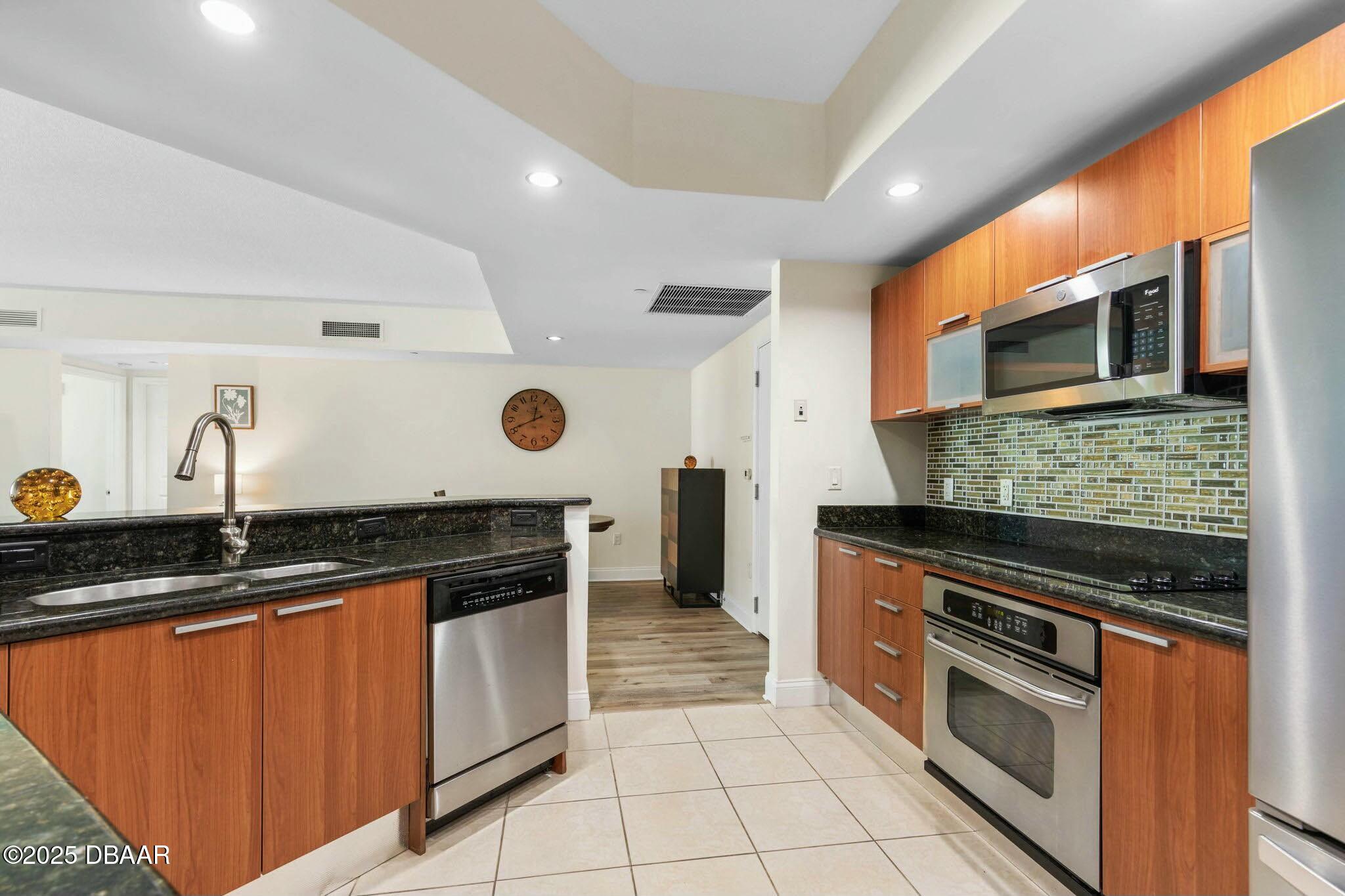 231 Riverside Drive, Unit 1104 Holly Hill, FL 32117 - Photo 23 of 77 a kitchen with stainless steel appliances granite countertop a stove a sink and a microwave