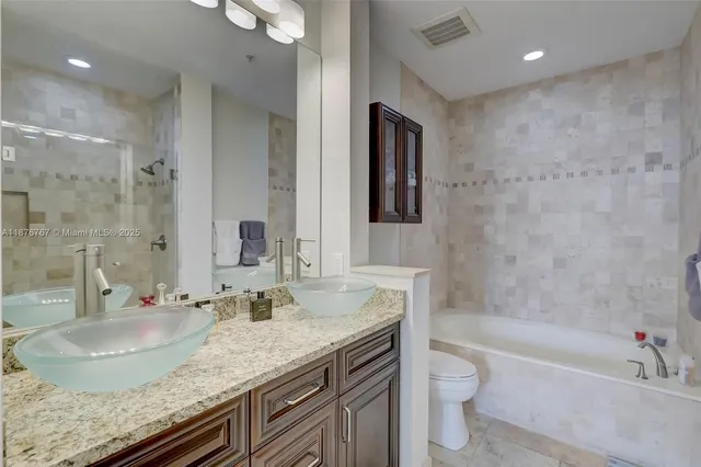 a bathroom with a granite countertop sink a toilet and bathtub