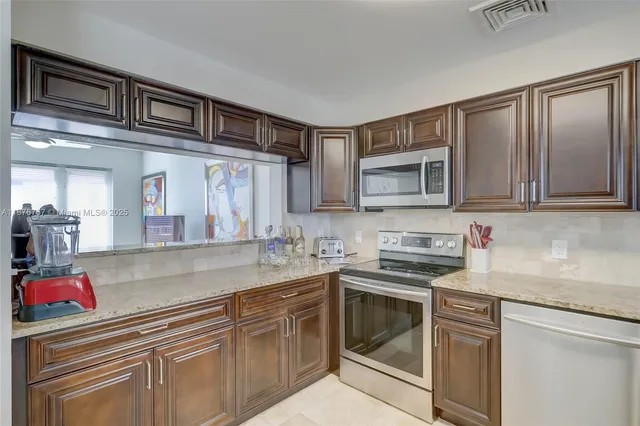 a kitchen with stainless steel appliances granite countertop a sink dishwasher stove and cabinets