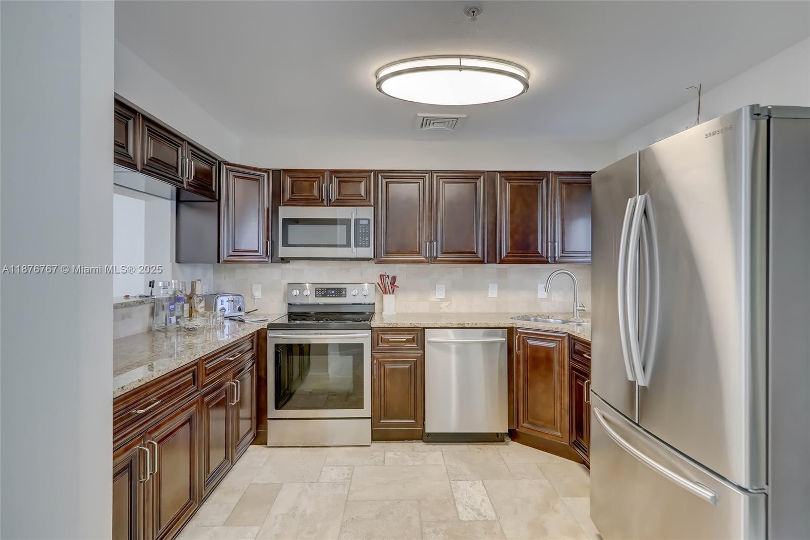 2039 Oceanwalk Lane, Unit 401 Pompano Beach, FL 33062 - Photo 4 of 12 a kitchen with stainless steel appliances granite countertop a stove top oven a sink dishwasher a refrigerator and a microwave