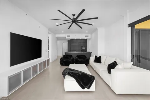 a living room with furniture a flat screen tv and a ceiling fan