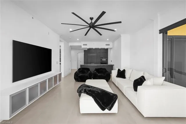 a living room with furniture a flat screen tv and a ceiling fan
