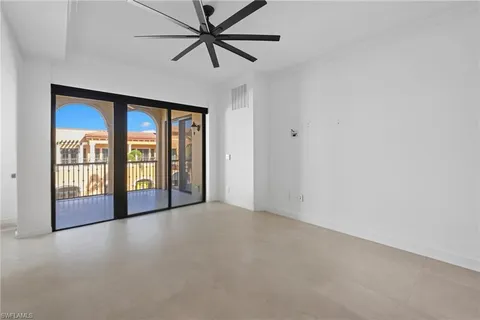 an empty room with chandelier fan and windows