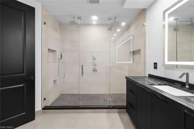 a bathroom with a granite countertop sink a toilet a mirror and shower
