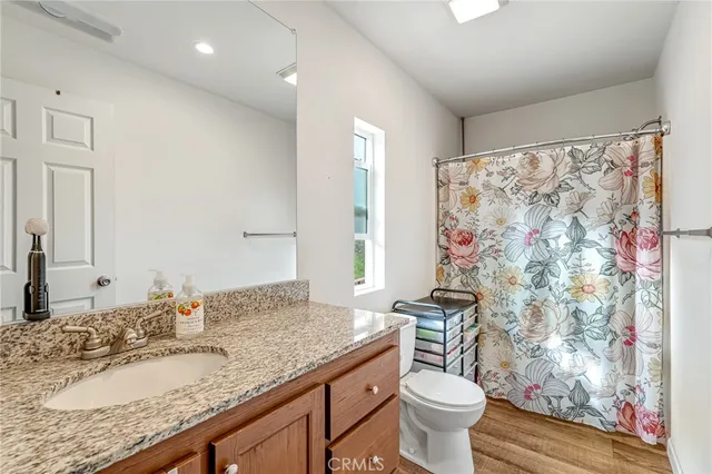 a bathroom with a granite countertop sink a toilet and a mirror