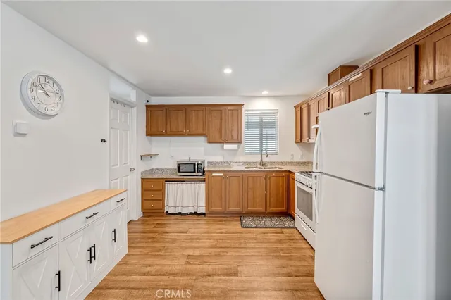 a kitchen with a refrigerator a stove top oven a sink and dishwasher with wooden floor