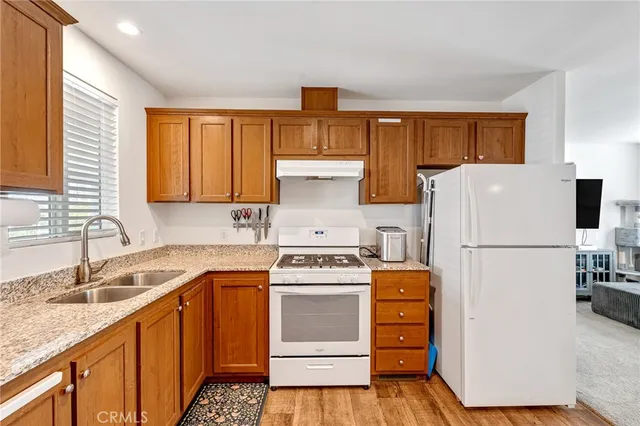 a kitchen with a refrigerator a stove a sink dishwasher and wooden cabinets with wooden floor