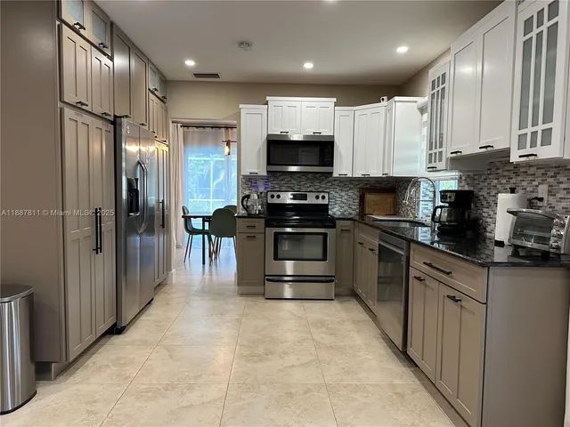 a large kitchen with stainless steel appliances granite countertop a stove top oven a sink and a refrigerator