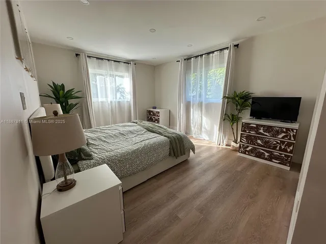 a bedroom with a bed a large window and a flat screen television