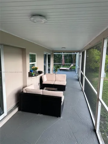 a living room with furniture floor to ceiling window and a potted plant