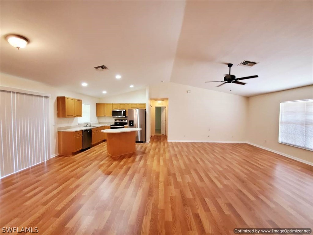 4652 27th Street Southwest Lehigh Acres, FL 33973 - Photo 3 of 21 a view of a kitchen with kitchen island a sink wooden floor and a refrigerator