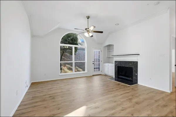 a view of an empty room with wooden floor fireplace and a window