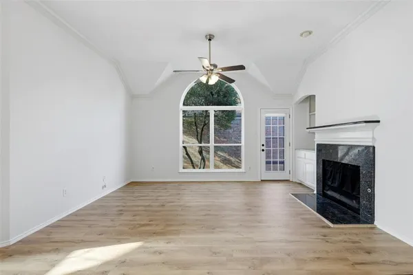 a view of an empty room with wooden floor fireplace and a window