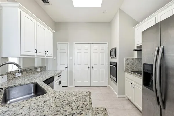 a kitchen with granite countertop a sink stove and cabinets
