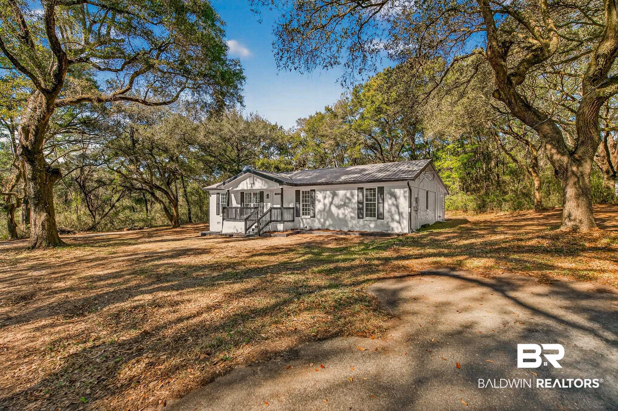 10650 Old Pascagoula Road Theodore, AL 36582 - Photo 7 of 77 View of front facade featuring view of wooded area, a metal roof, and a front yard