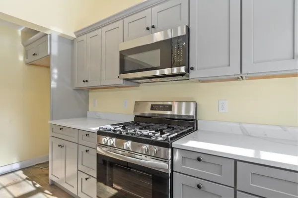 a kitchen with stainless steel appliances granite countertop white cabinets and a stove a oven with wooden floors