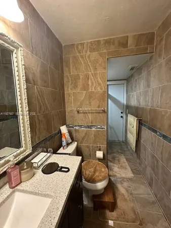 a bathroom with a granite countertop sink a toilet a mirror and shower