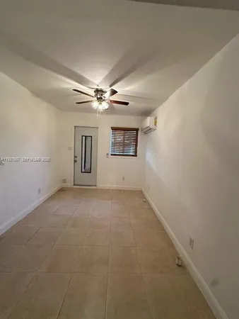 an empty room with chandelier fan and windows