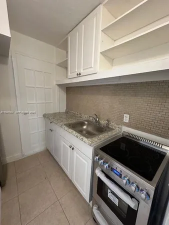 a kitchen with a stove a sink and cabinets