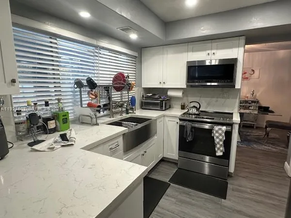a kitchen with stainless steel appliances kitchen island granite countertop a stove a sink and a microwave