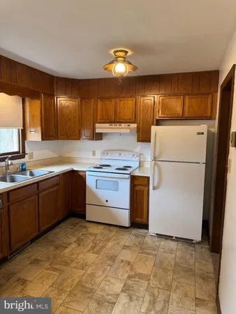 a kitchen with a sink a stove a refrigerator a kitchen island and a window