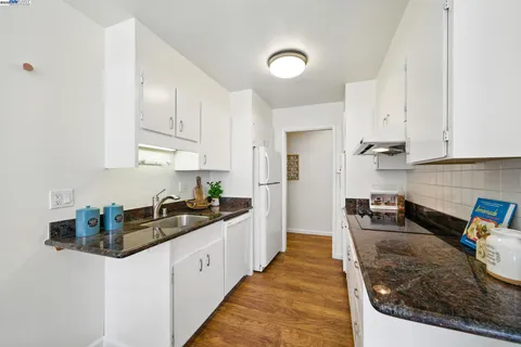 a kitchen with granite countertop a sink a stove and refrigerator