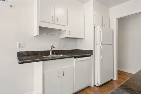 a kitchen with granite countertop a sink and a refrigerator