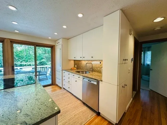 a kitchen with stainless steel appliances granite countertop a refrigerator a sink dishwasher and wooden cabinets with wooden floor