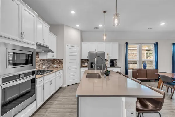 a kitchen with stainless steel appliances a dining table chairs stove microwave and cabinets