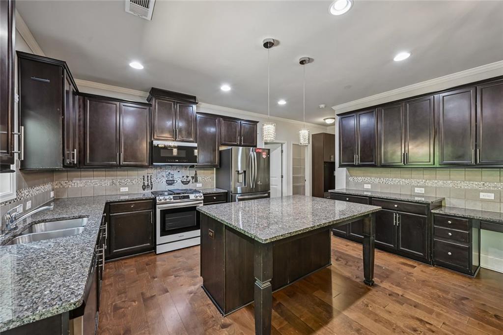 5378 Silverwoods Walk Powder Springs, GA 30127 - Photo 12 of 62 a kitchen with stainless steel appliances granite countertop a sink stove and refrigerator
