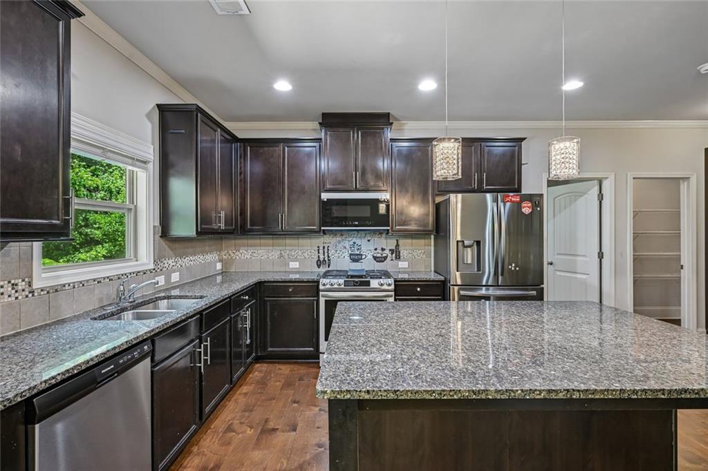5378 Silverwoods Walk Powder Springs, GA 30127 - Photo 16 of 62 a kitchen with stainless steel appliances granite countertop a sink stove and refrigerator