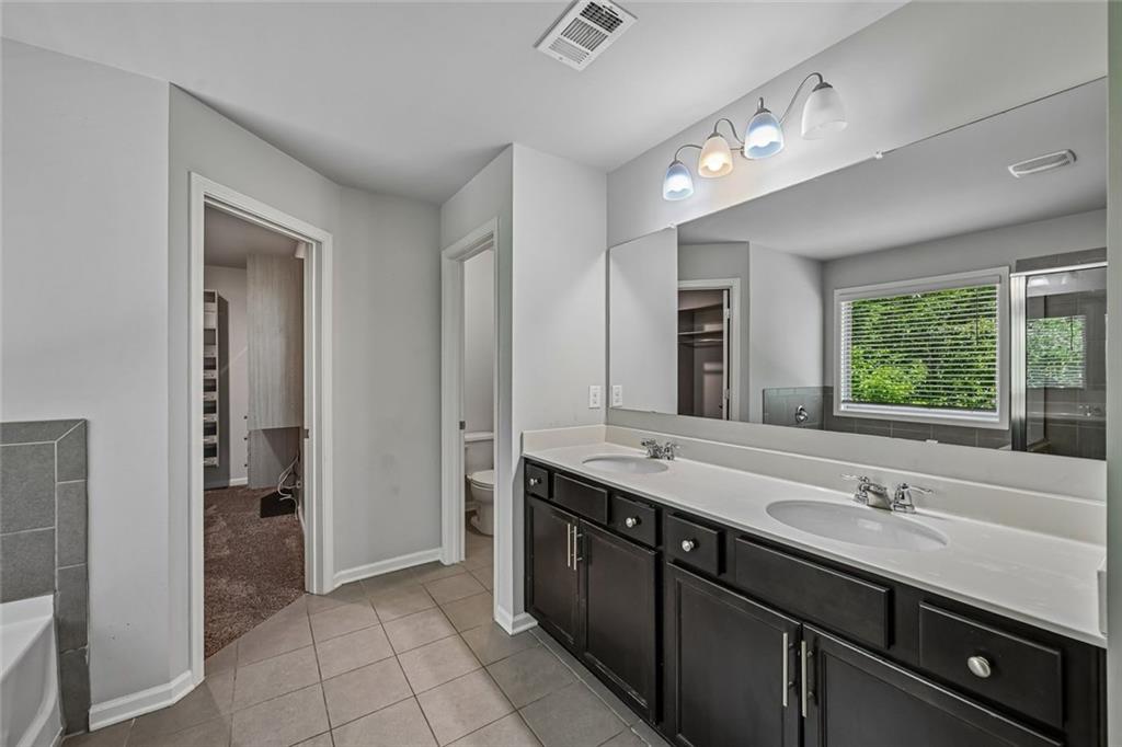 5378 Silverwoods Walk Powder Springs, GA 30127 - Photo 31 of 62 a spacious bathroom with a double vanity sink a large mirror and a bathtub