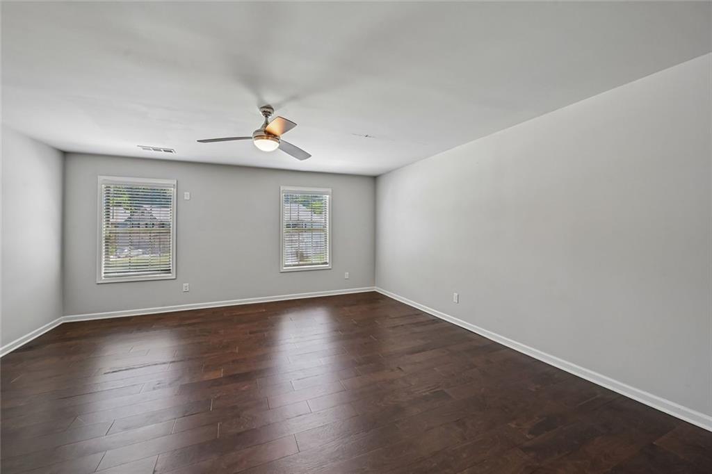 5378 Silverwoods Walk Powder Springs, GA 30127 - Photo 42 of 62 an empty room with wooden floor chandelier fan and windows