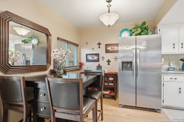 a kitchen with stainless steel appliances granite countertop a refrigerator a sink dishwasher a dining table and chairs with wooden floor